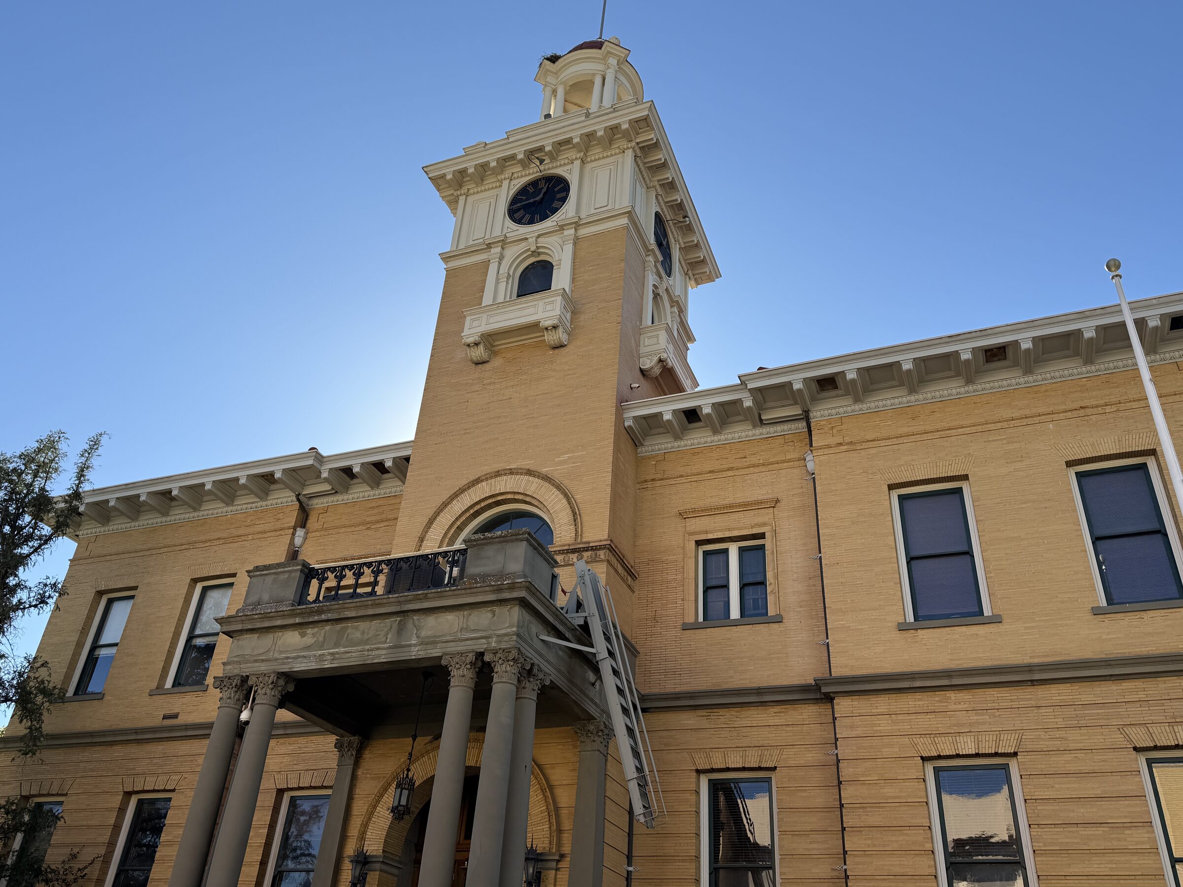 The yellow Tuolumne County Courthouse and its clock tower against a blue sky in Sonora